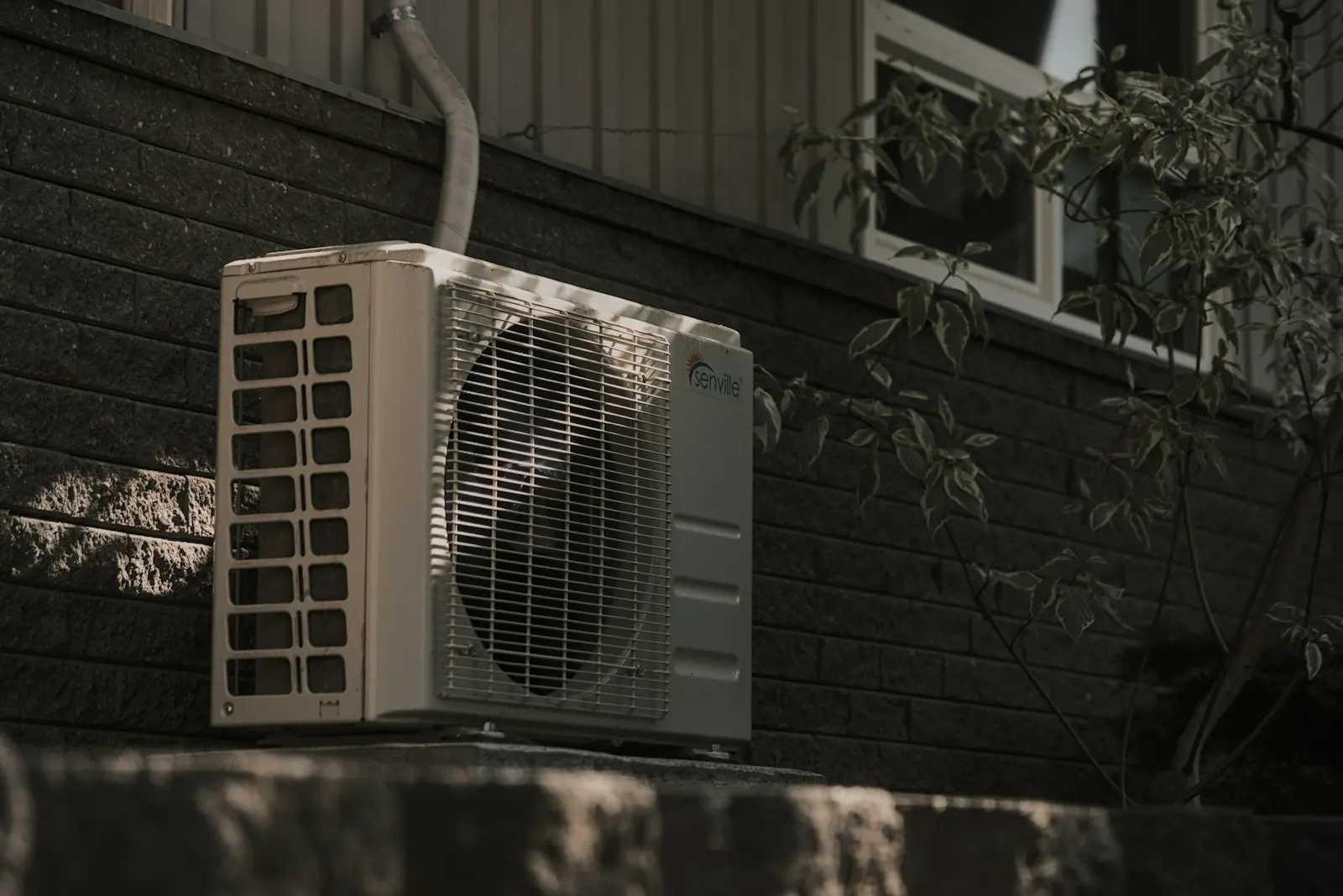 a white air conditioner sitting on top of a brick wall